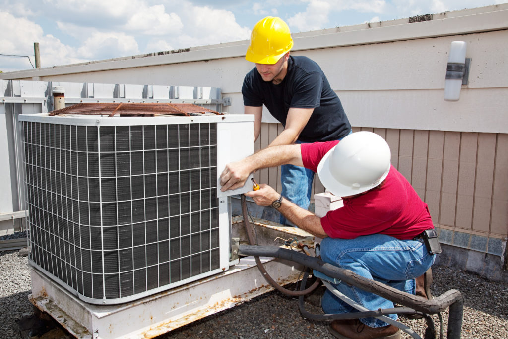 technicians performing maintenance on top of a commercial building