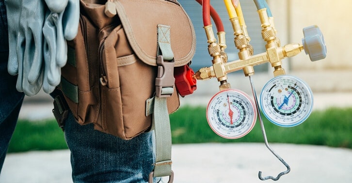 closeup of hvac technician supply bag with pressure checker hanging out of it