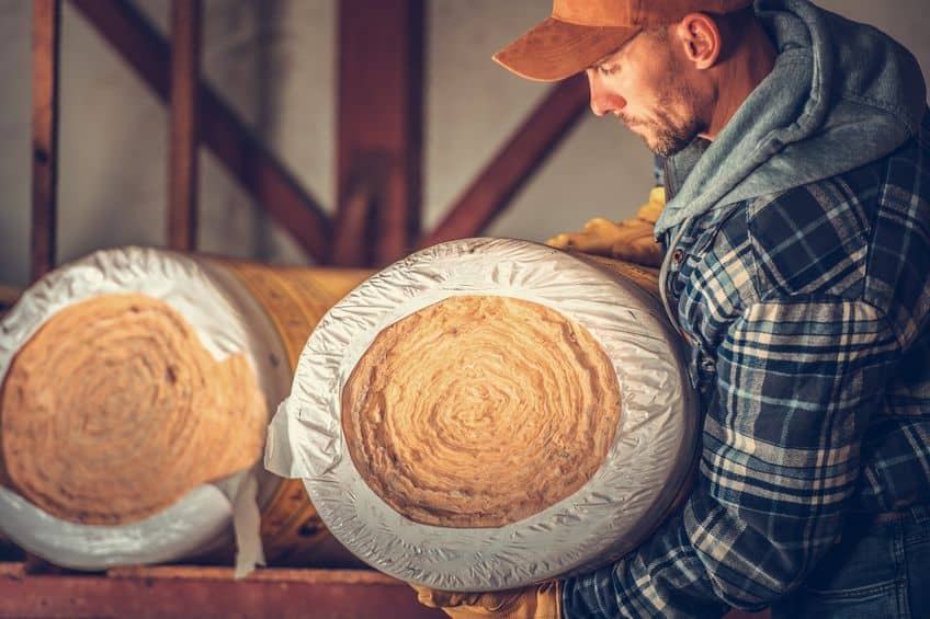 technician grabbing a roll of attic insulation as he's about to install it in the attic of an austin home