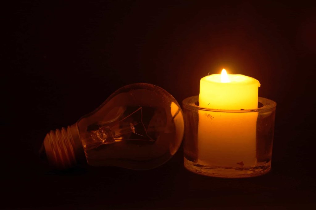 Burning candle and lamp on desktop in darkness