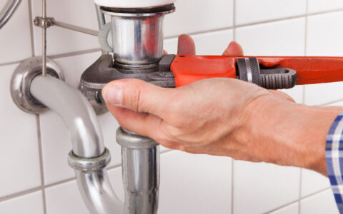 Close-up Of Male Plumber Fitting Sink Pipe In Bathroom