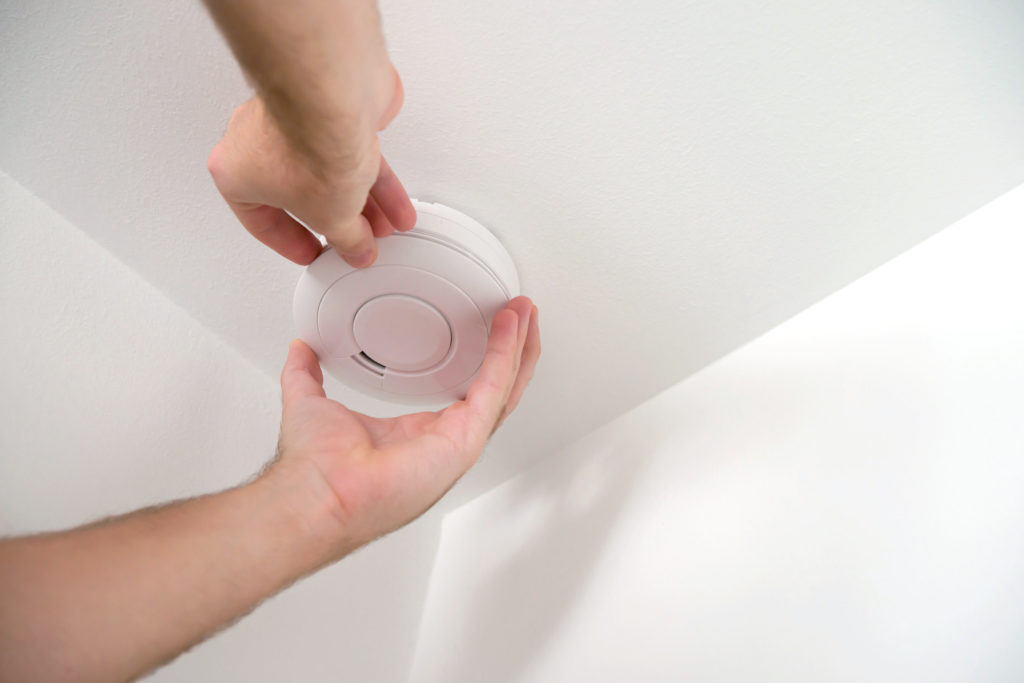 hands installing smoke detector or carbon monoxide detector