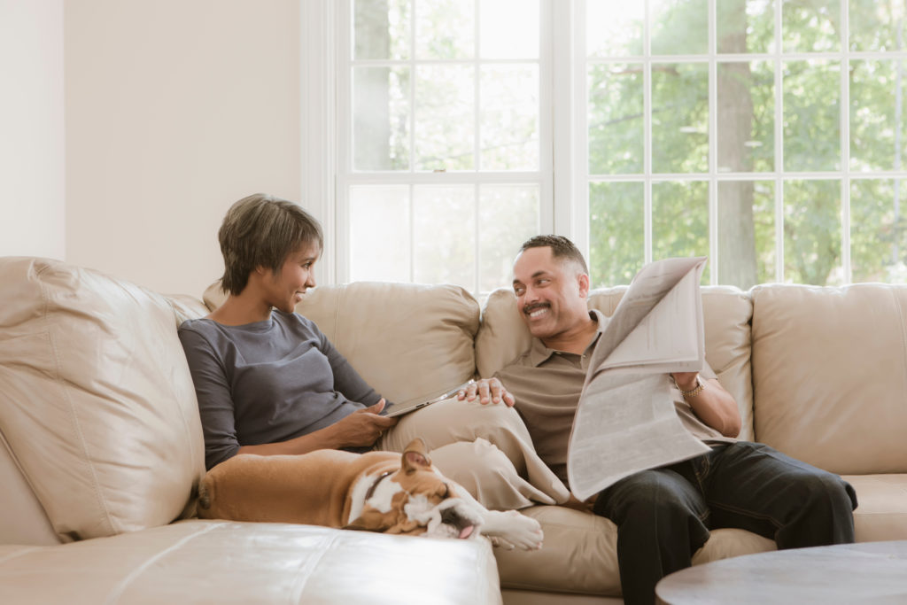couple sitting on couch relaxing with their english bulldog