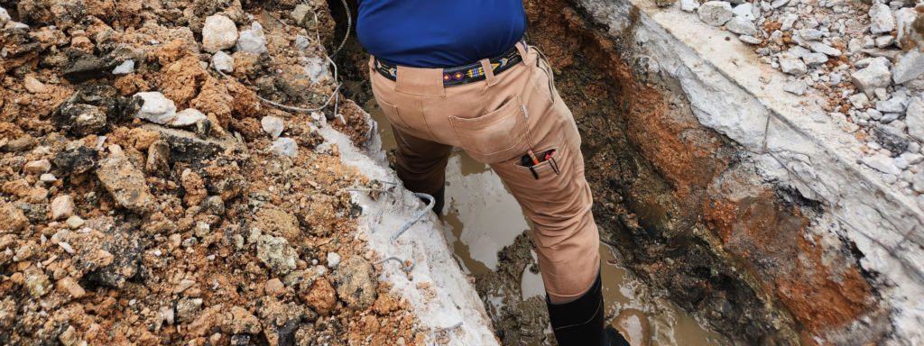 champion ac and plumbing professional getting down and dirty to repair a sewer line