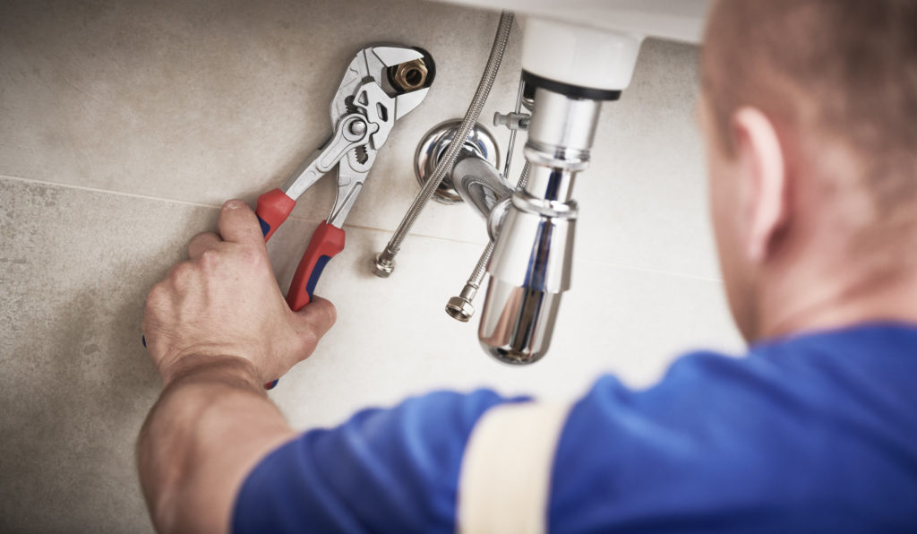 plumber performing plumbing services under sink