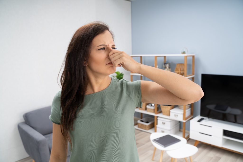 woman covering her nose to block smell of burning heater