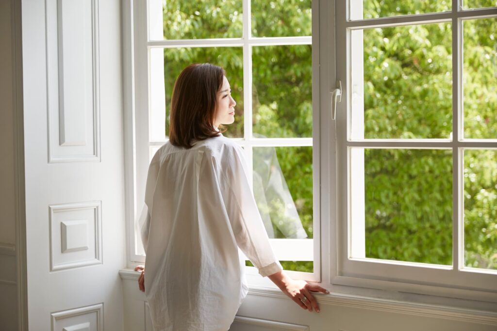 homeowner standing in front of an open window in her home