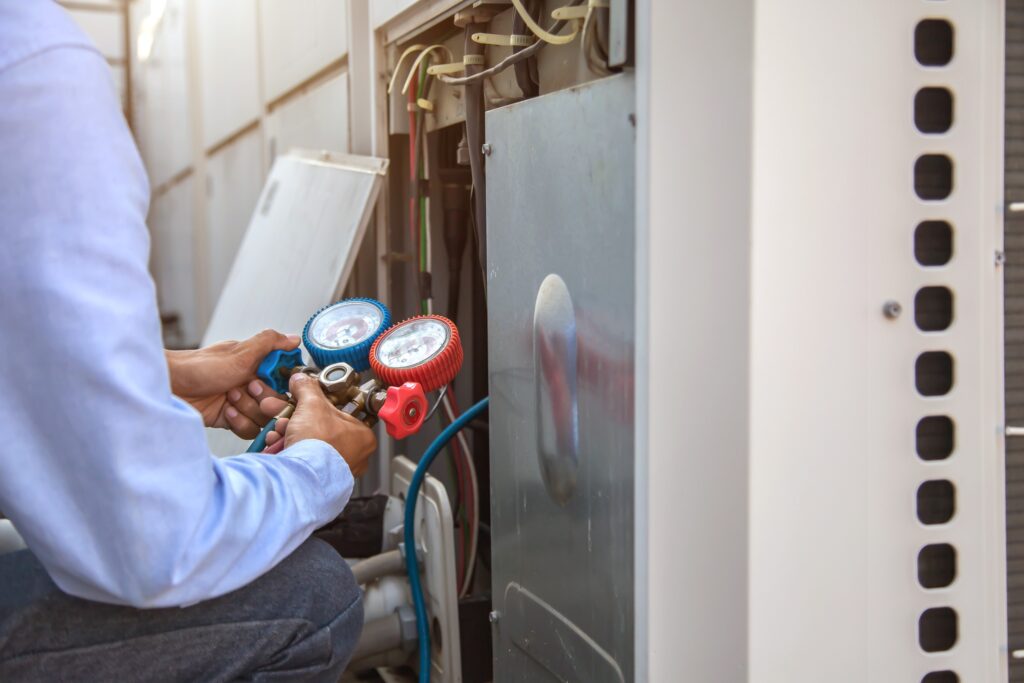 hvac technician using a pressure gauge to perform maintenance on a furnace
