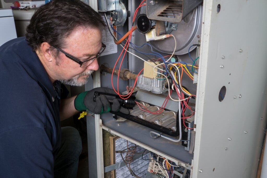 hvac technician inspecting a furnace system for a leak